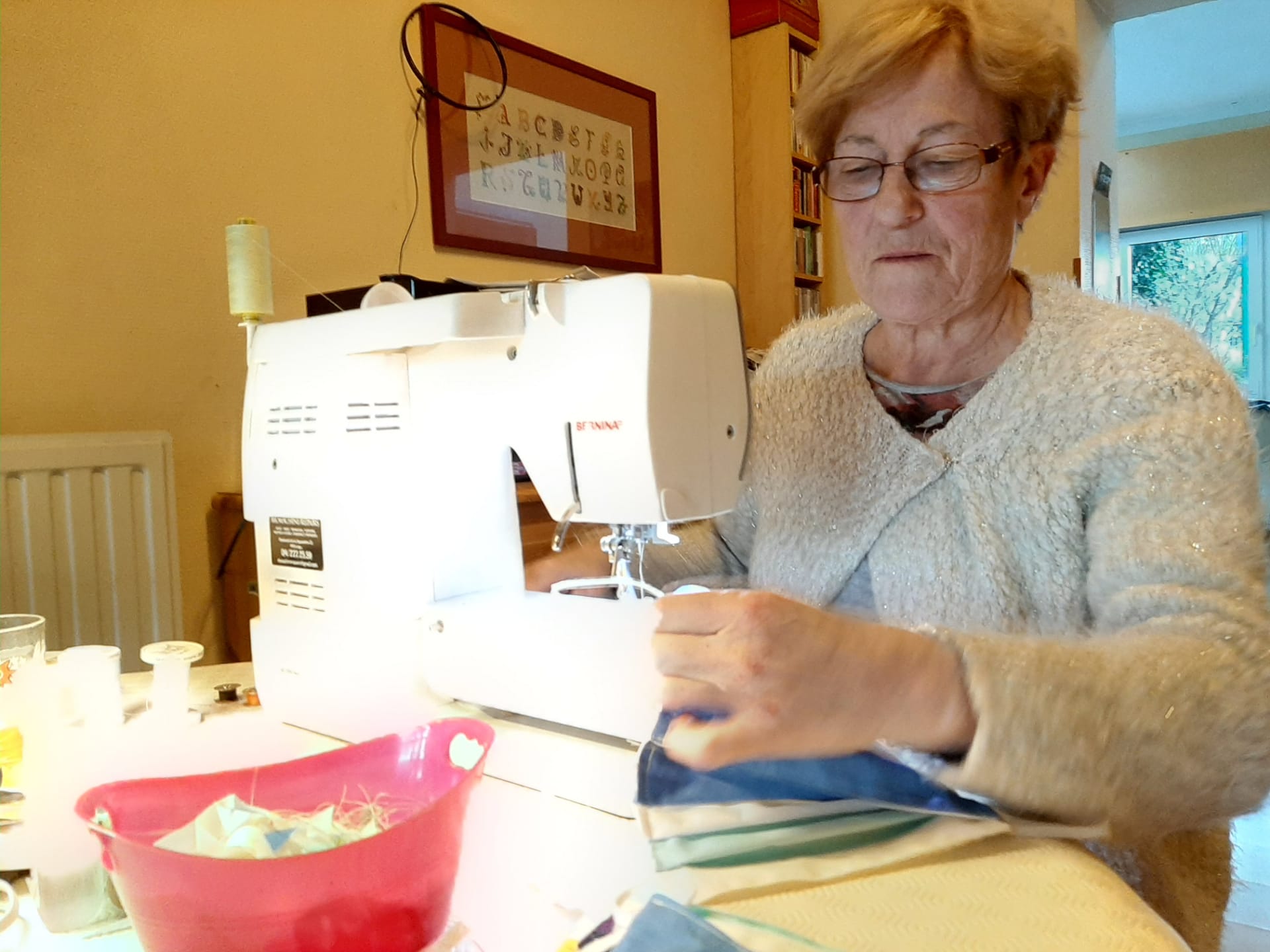 La coordinatrice de l'asbl affairée devant sa machine à coudre.